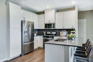Premium kitchen featuring dark quartz countertops and white cabinetry in a two bedroom penthouse Princeton floor plan