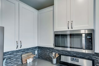 Premium kitchen with custom tile backsplash, dark quartz countertops at Ascend at Woodbury best new apartments Woodbury MN 55129