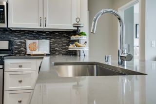 Premium kitchen featuring upgraded appliances and a gas range, dark quartz countertops and white cabinetry at Ascend at Woodbury best new apartments Woodbury MN 55129