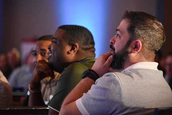 Two men are sitting in a room with blue lighting.