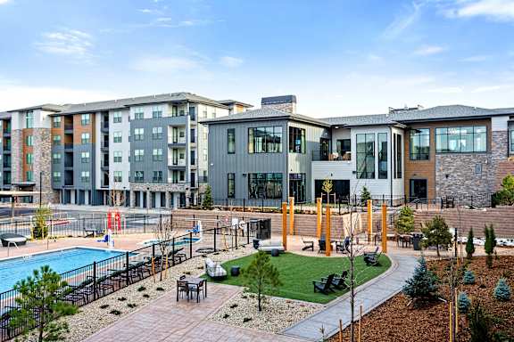 A modern apartment complex with a pool and outdoor seating area.