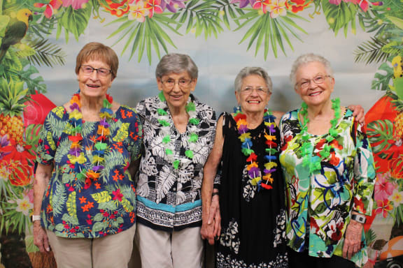 a group of women standing together in front of a tree
