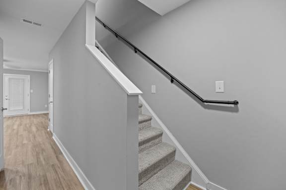 A staircase with a black handrail and wooden steps.