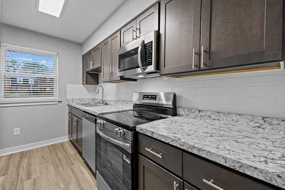 A kitchen with a marble countertop and stainless steel appliances.