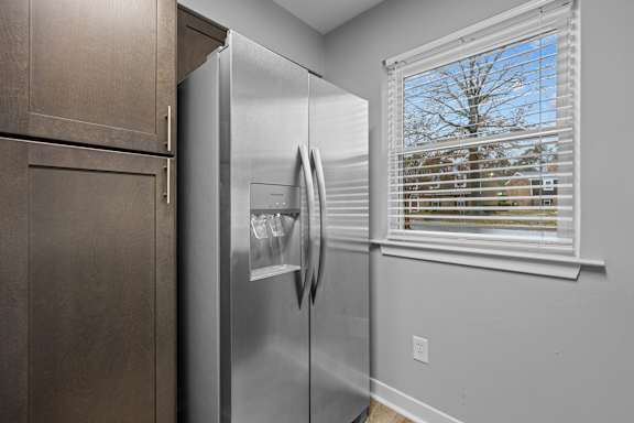 A stainless steel refrigerator in a kitchen with brown cabinets.
