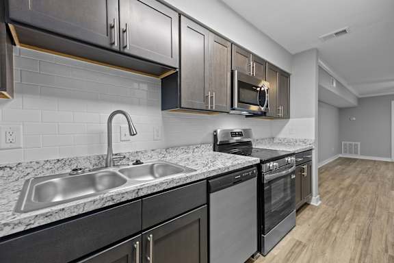 A modern kitchen with a sink, stove, and microwave.