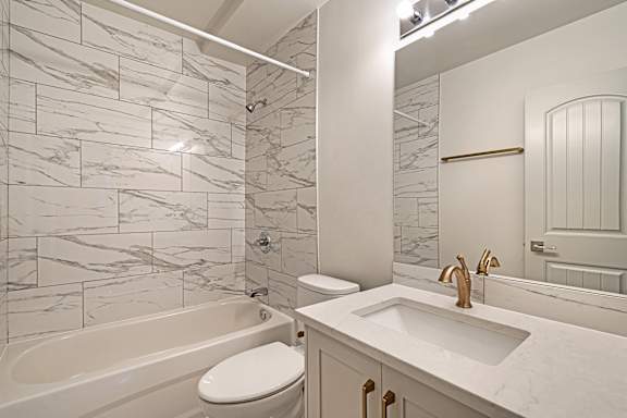 A white bathroom with a marble tile wall and a white toilet.