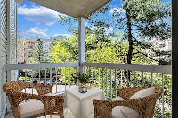 A balcony with a table and chairs overlooking a tree.
