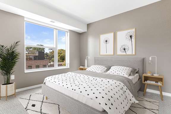 A bedroom with a large bed and a view of a building outside the window.