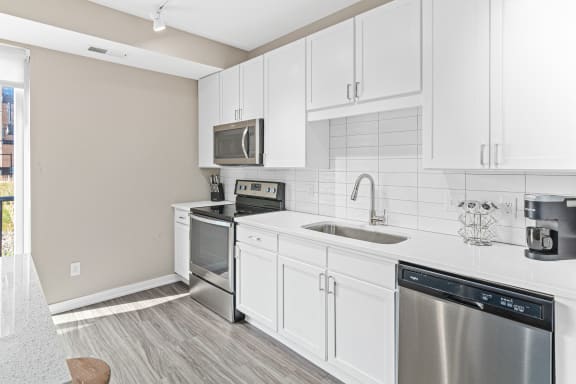 a white kitchen with stainless steel appliances and white cabinets