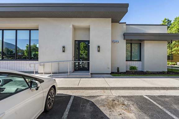 A white car is parked in front of a modern building.