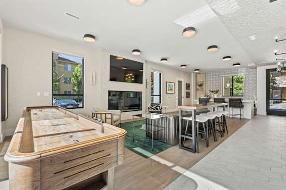 A billiard table is in the middle of a room with a kitchen and dining area.