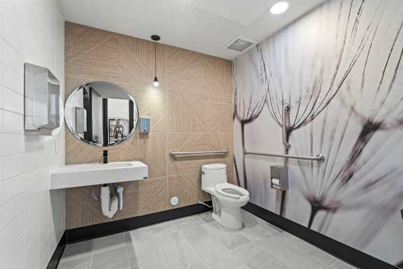 A bathroom with a toilet, sink, and a wallpaper of a flower.