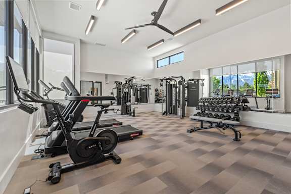A spacious gym with a variety of equipment including treadmills, elliptical machines, and dumbbells.