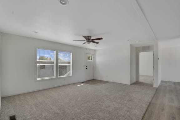 a living room with white walls and a ceiling fan