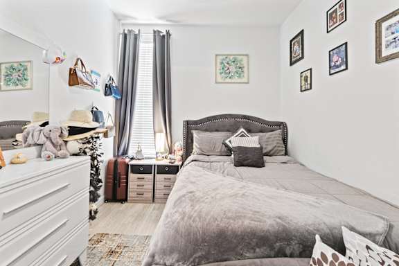 A bedroom with a large bed and a white dresser.