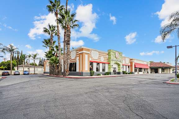 A parking lot in front of a building with palm trees.