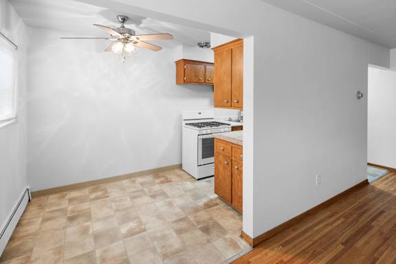 A kitchen with a fan and wooden cabinets.