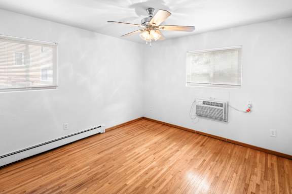 A room with a ceiling fan and wooden flooring.