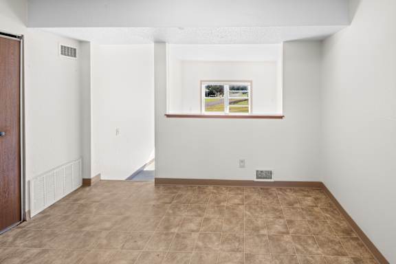 A room with a brown tile floor and a painting on the wall.