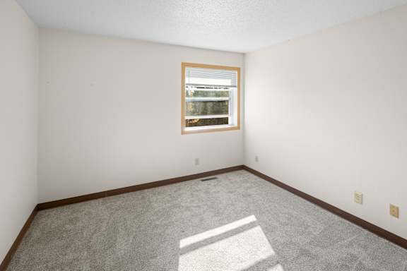 A room with a window and carpeted floor.