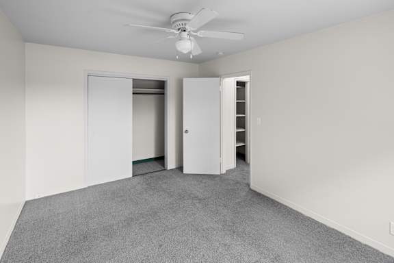 A room with a ceiling fan and two open doors.
