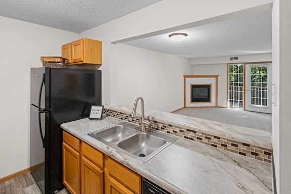 A kitchen with a black fridge and a marble counter top.