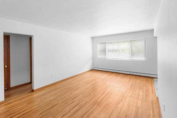 A room with wooden flooring and a window with blinds.