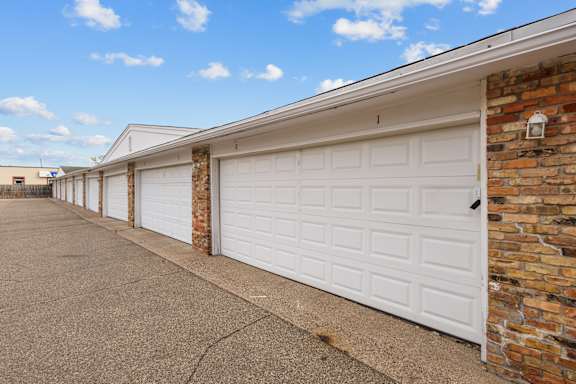 A row of garage doors in front of a brick wall.