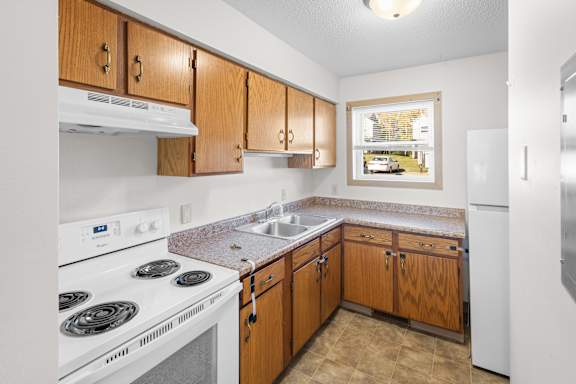 A kitchen with white appliances and wooden cabinets.