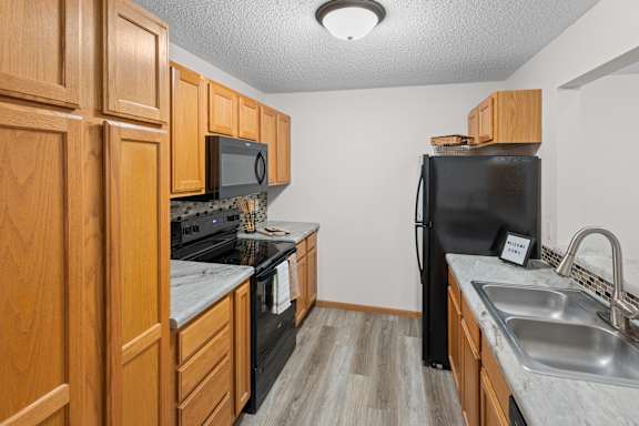 A kitchen with black appliances and wooden cabinets.