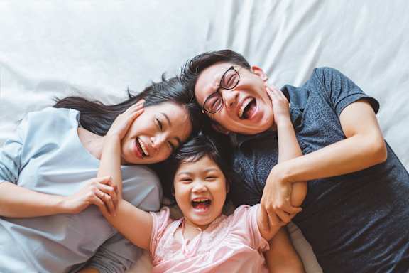 A family of three is lying down together on a bed.