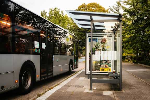 A bus is parked at a bus stop with a shelter and a sign.