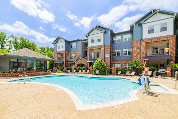 A large swimming pool in front of a multi-story apartment building.