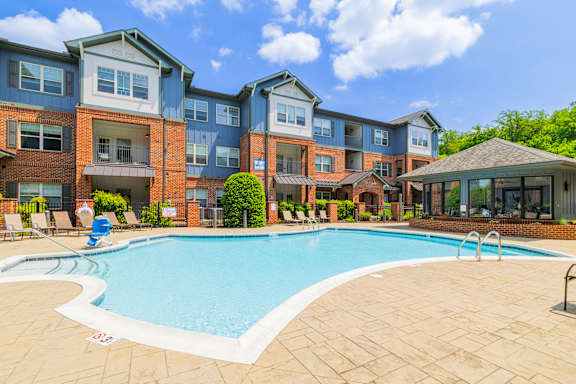 A swimming pool in front of a multi-story apartment building.