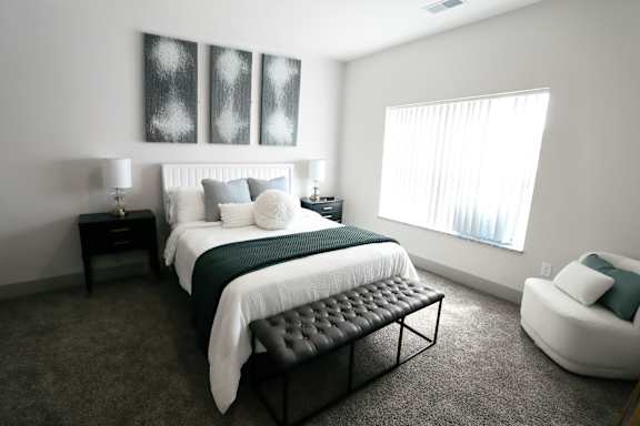 A bedroom with a large bed and a chair.