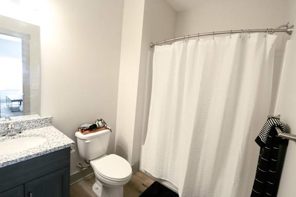 A white shower curtain hangs in a bathroom.