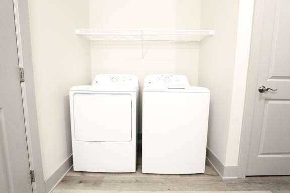 Two white washing machines in a small laundry room.