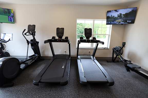 A room with a treadmill, a stationary bike, and a rowing machine.