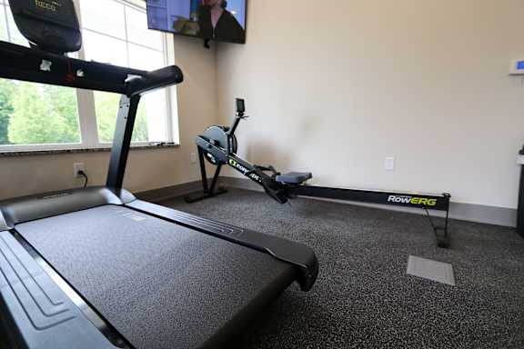A treadmill and rowing machine in a room.