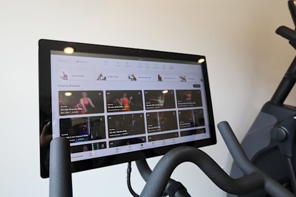 A tablet is mounted on a bike handlebar displaying a fitness app.