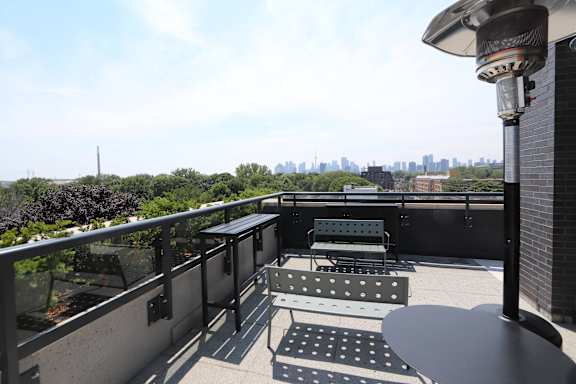A balcony with a table and chairs overlooking a city skyline.