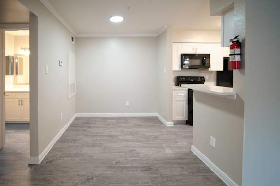 a renovated kitchen with a hard wood floor and white cabinets