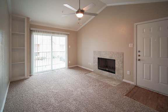 an empty living room with a fireplace and a ceiling fan