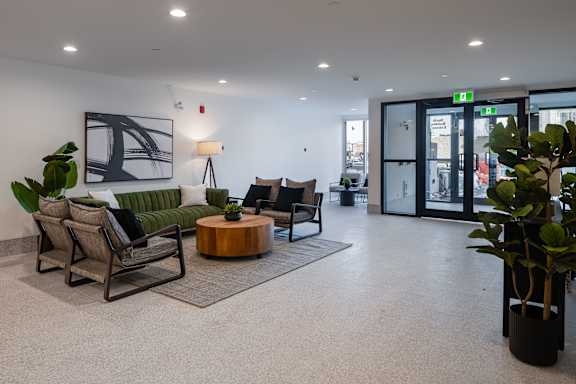 A modern waiting area with a green couch, wooden coffee table, and a large artwork on the wall.