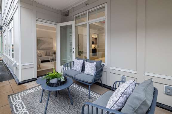 A grey sofa with a plant on a table in front of it.