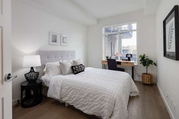 A bedroom with a large bed and a desk with a chair.