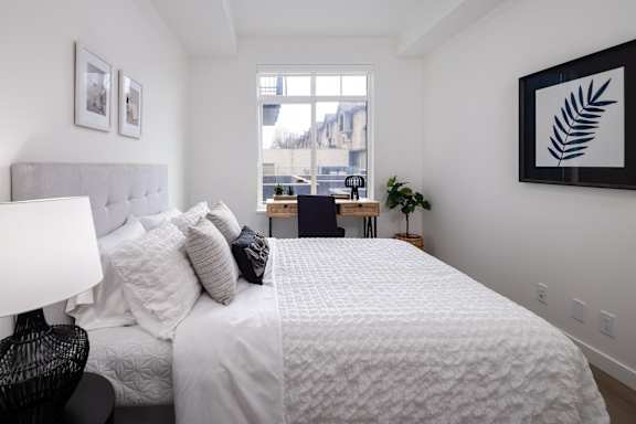 A bedroom with a large bed and a window overlooking a cityscape.