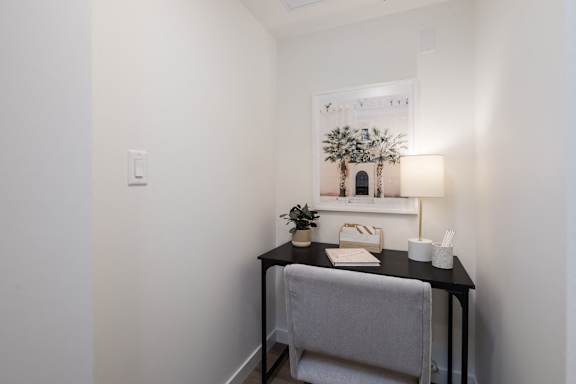 A small table with a chair and a potted plant sits in a corner of a room.