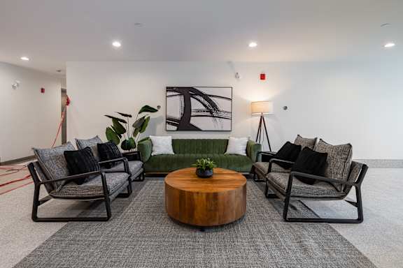 A modern living room with a green couch, a coffee table, and a large painting on the wall.